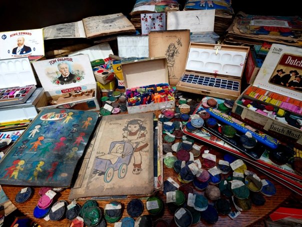 Art materials, sketches of a little girl, paint, and pastels.
