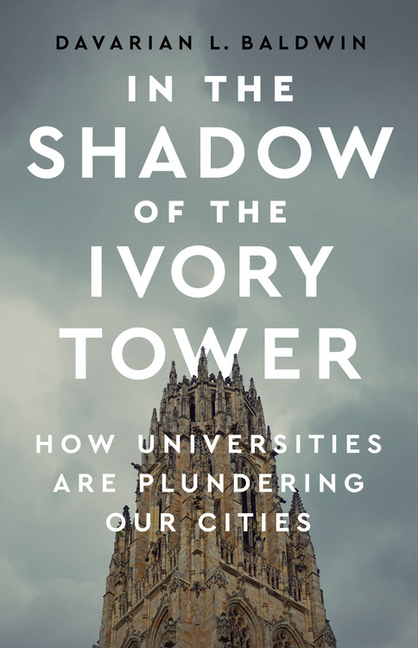 In the Shadow of the Ivory Tower: How Universities Are Plundering Our Cities book cover: photograph of university building tower framed against cloudy sky. Book title in white bold text and author name in black bold text.